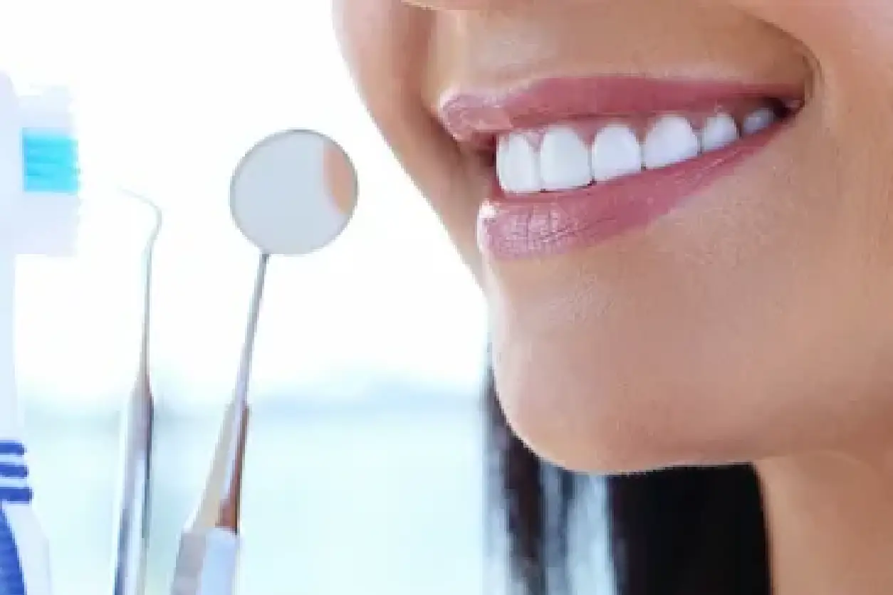 A woman smiles while holding a tooth brush.