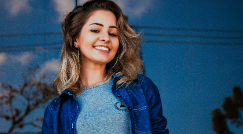 A woman with long hair smiles while wearing a blue jacket.