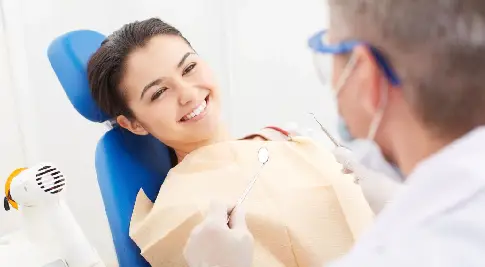 A woman sitting in the dentist chair with her teeth being examined.