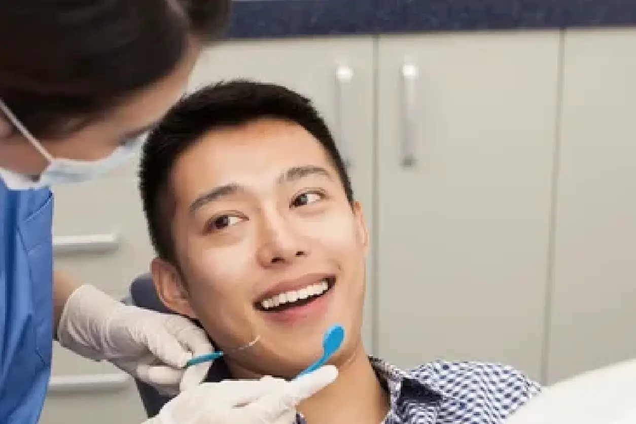 A man getting his teeth checked by an dentist.