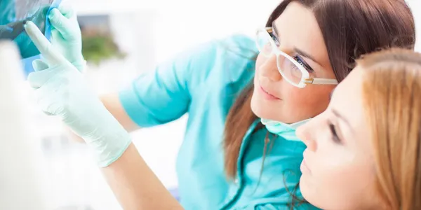 A woman in glasses and gloves talking on the phone.