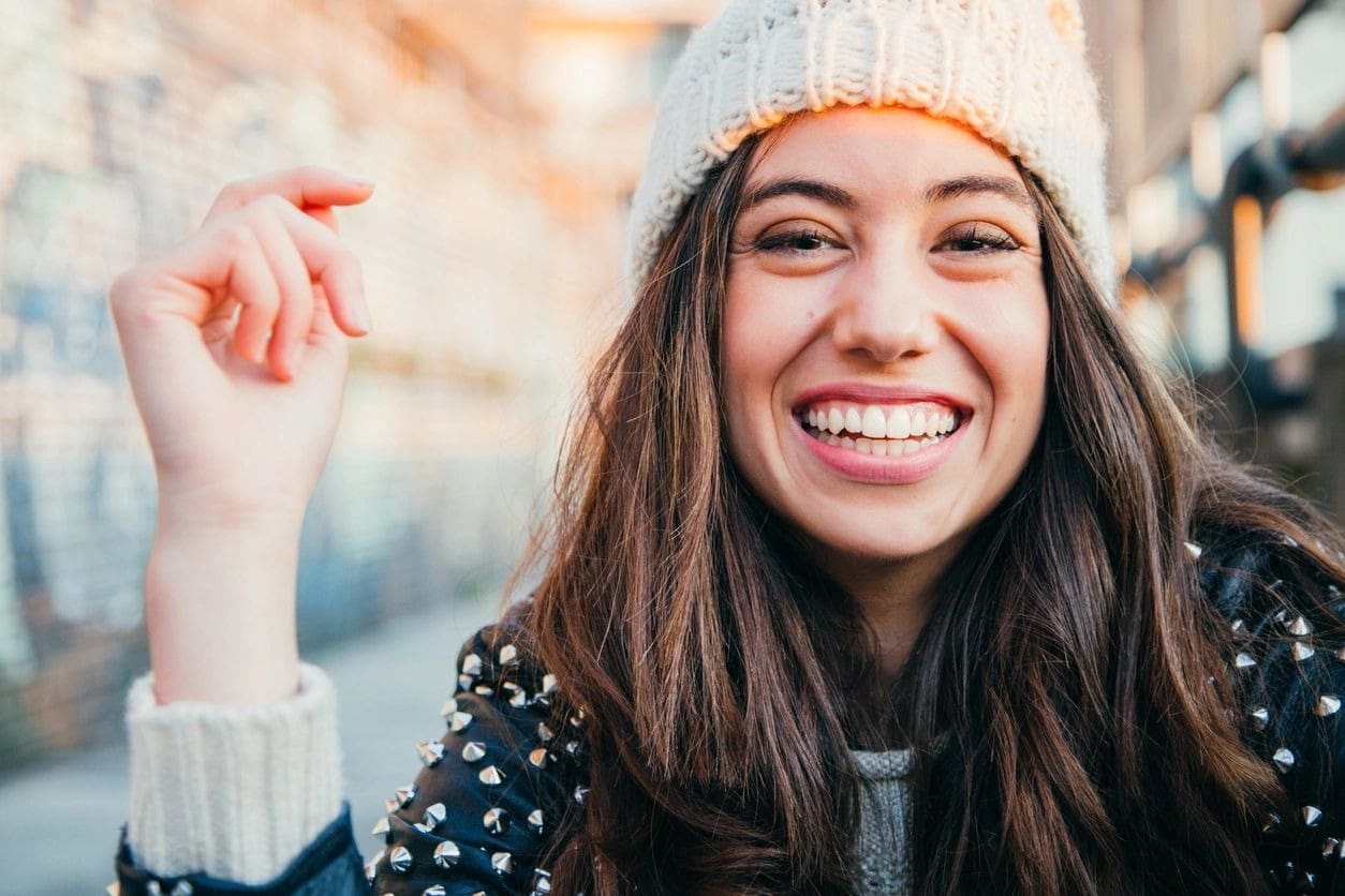 A woman wearing a white hat and smiling.