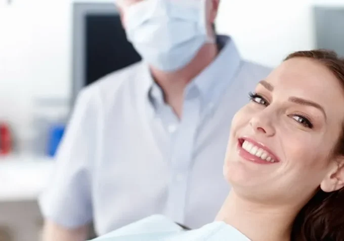 A woman smiles while sitting in the dentist 's chair.